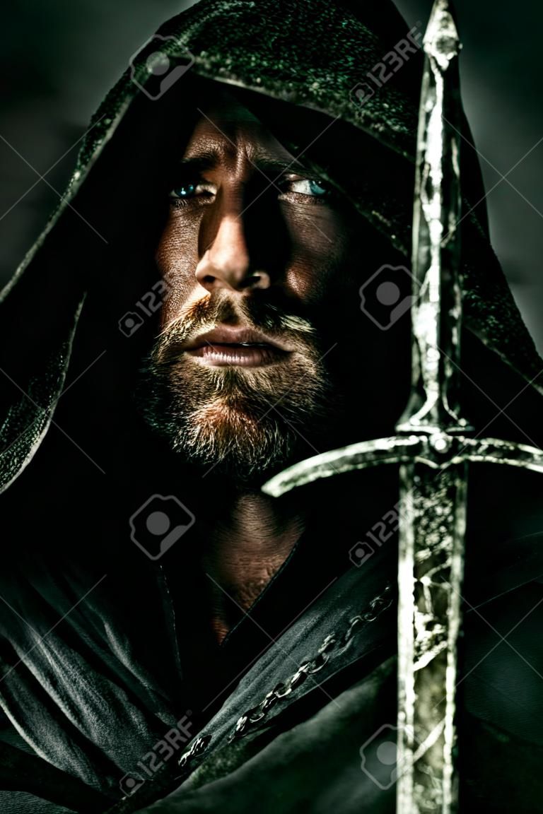 Portret odważnego wojownika wędrowca w czarnym płaszczu i mieczem w ręku