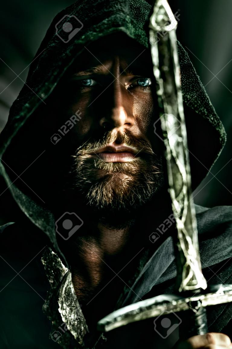 Retrato de un guerrero valiente trotamundos en un manto negro y una espada en la mano