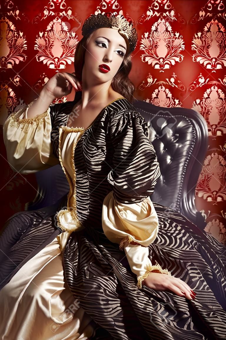 Giovane e bella signora in abito costoso lussureggiante in posa su sfondo vintage. Rinascimento. Barocco. Moda.