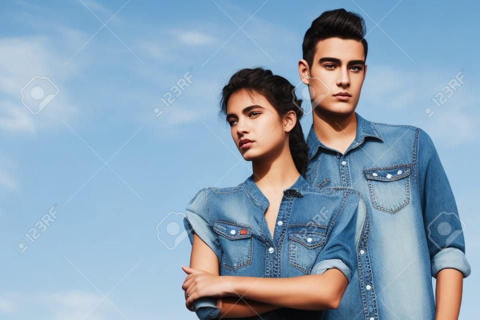 Ritratto di un moderno giovani che indossano jeans vestiti nel cielo blu. Moda girato.