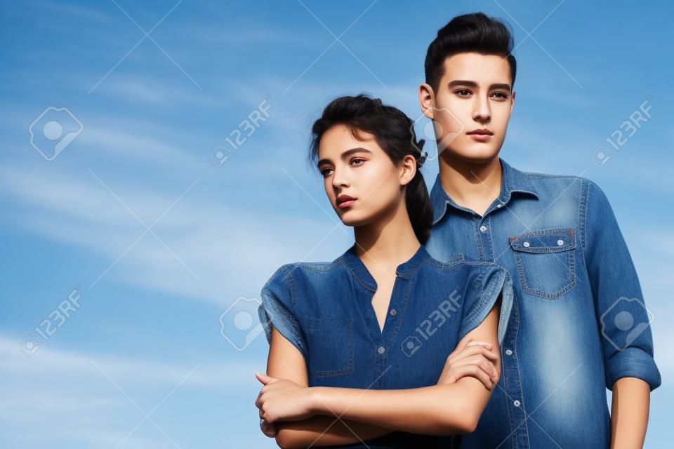 Ritratto di un moderno giovani che indossano jeans vestiti nel cielo blu. Moda girato.