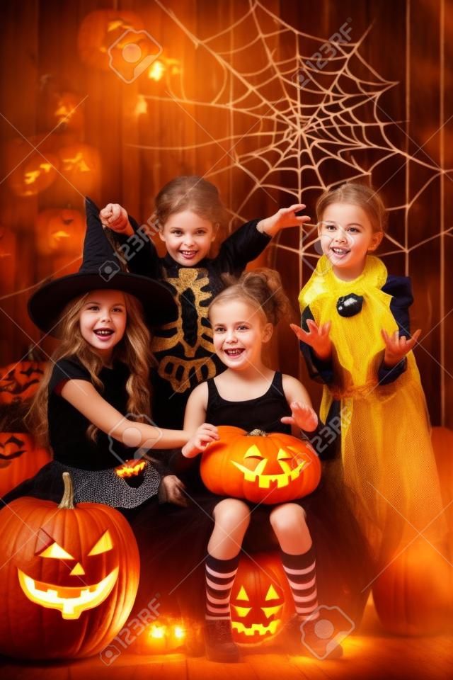 Wesoła dzieci w halloween kostiumy Świętuje Halloween w drewnianej stodole z dyni. Koncepcja Halloween.
