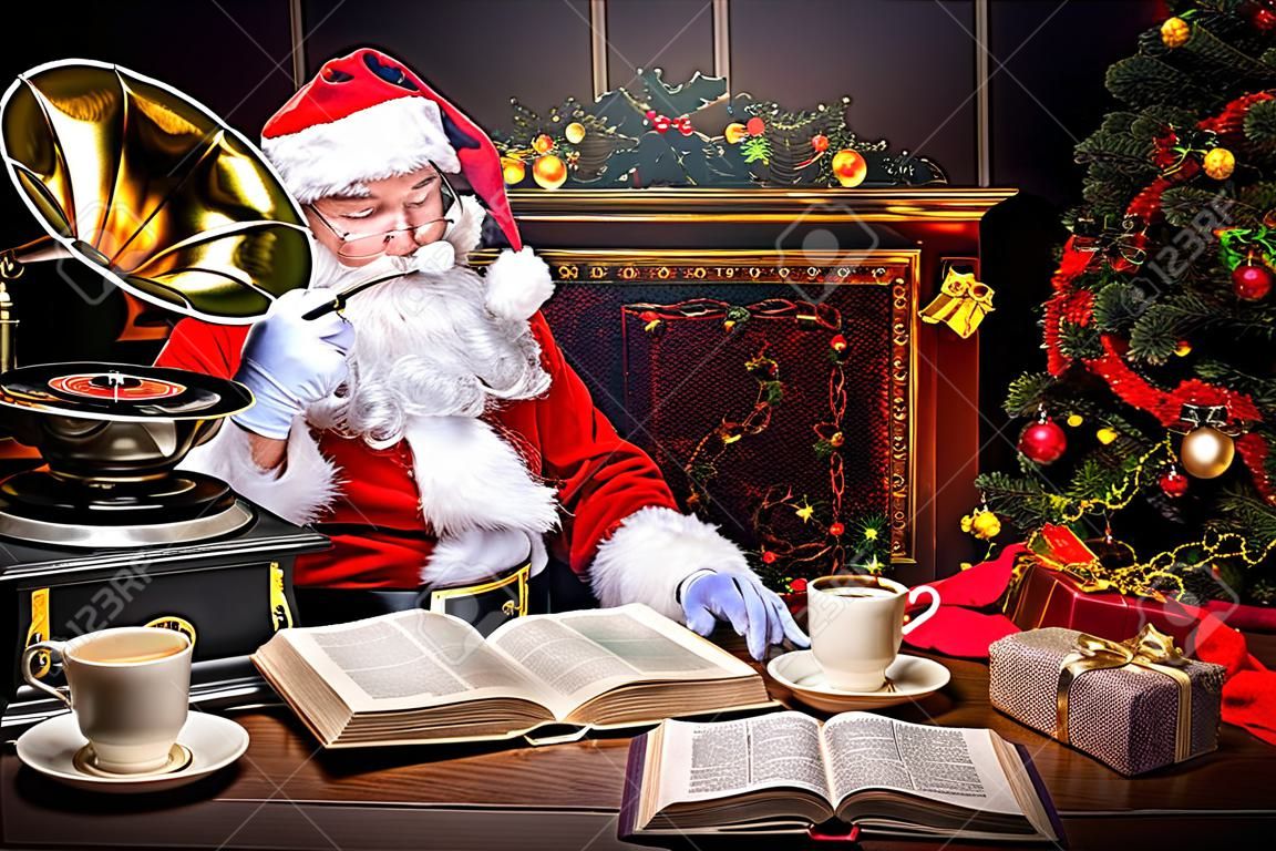 好老聖誕老人讀一本書，在家裡聽老留聲機。聖誕歌。聖誕節概念。
