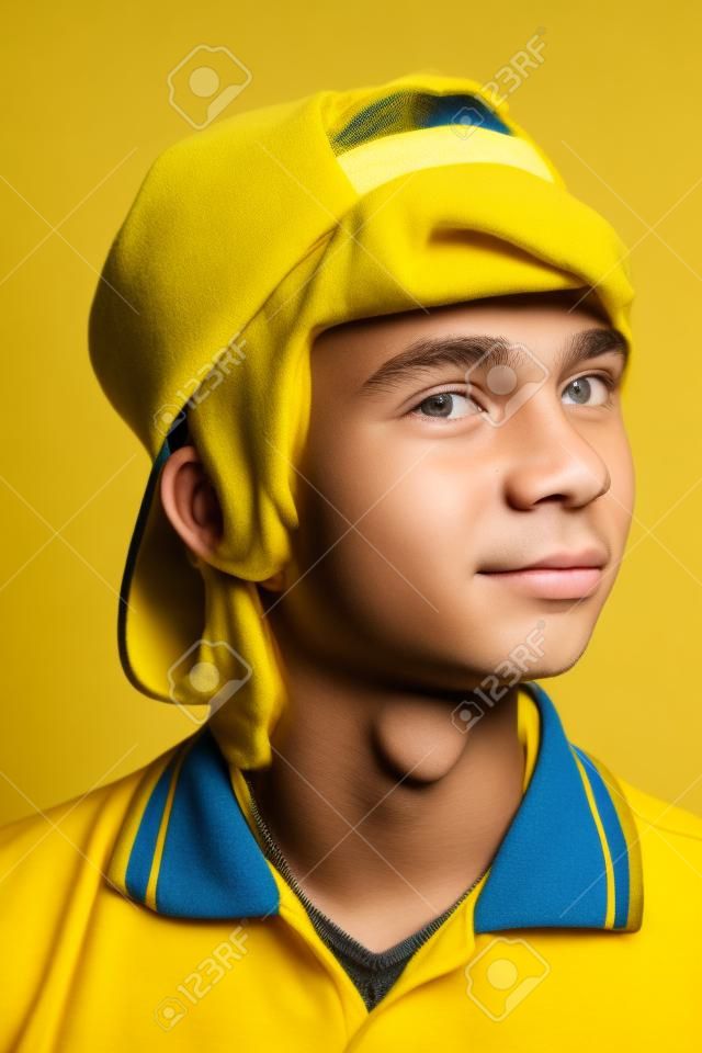Portrait of a smiling teenage boy over yellow background. Studio shot. Teen fashion.