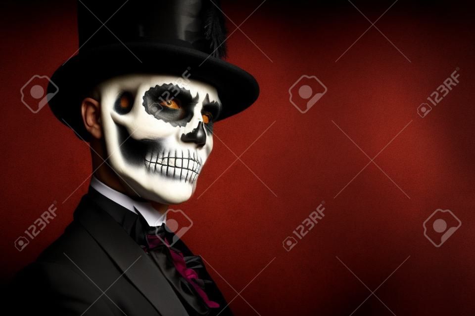 Retrato close-up de um homem com uma maquiagem de crânio vestido com um casaco de cauda e um top-hat. Barão sábado. Barão Samedi. Dia de los muertos. Dia dos Mortos. Halloween.