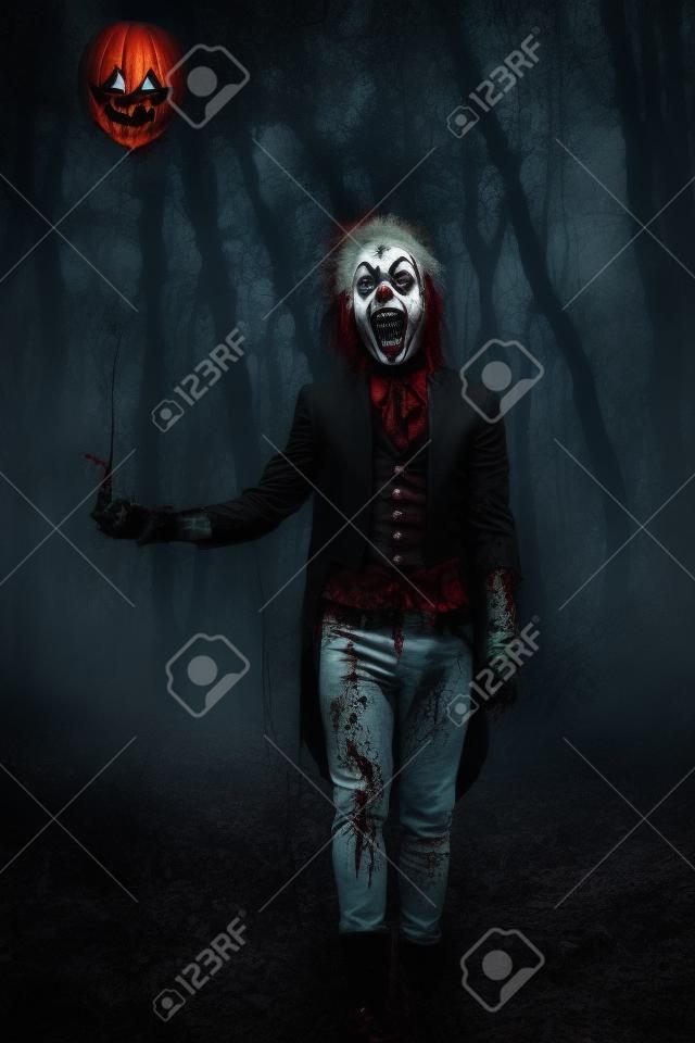 Portrait of a scary punk clown man smeared with blood in a night forest. Halloween. Horror, thriller film.