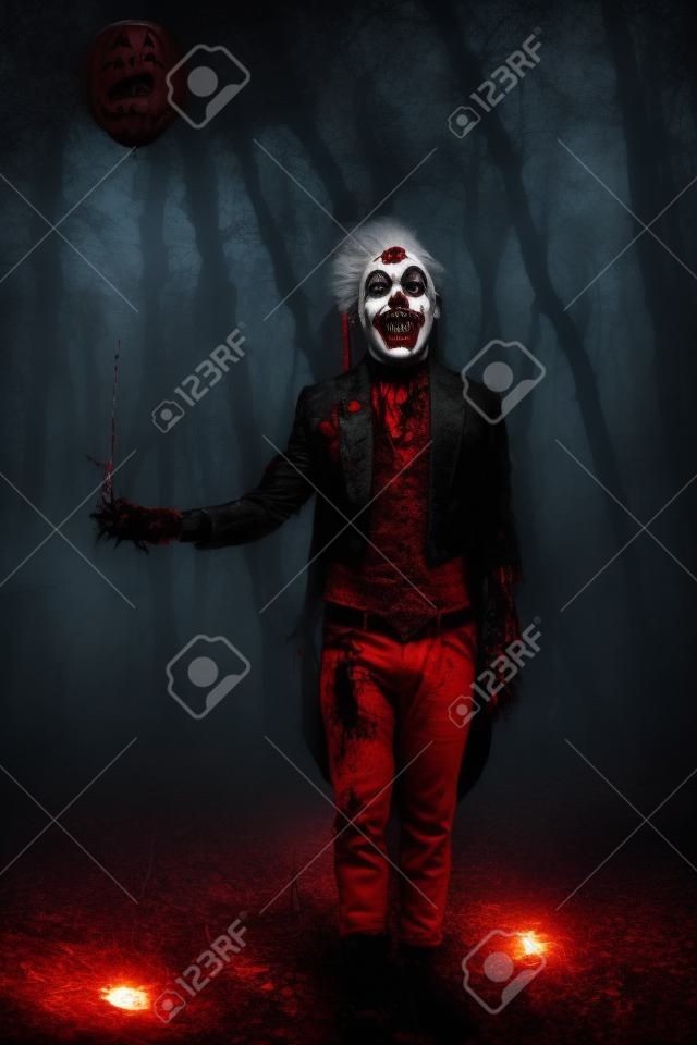 Portrait d'un homme de clown punk effrayant barbouillé de sang dans une forêt de nuit. Halloween. Horreur, thriller.