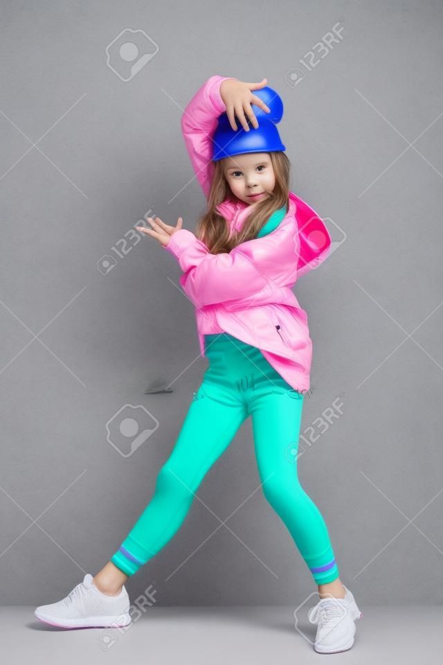 Pełne ujęcie jasnej emocjonalnej dziewczyny. Moda dla aktywnych dzieci.
