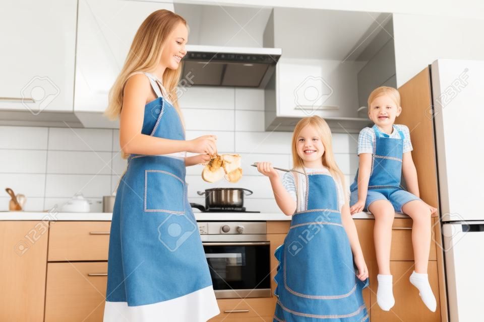 Une jeune femme avec ses enfants prépare un repas dans la cuisine. Shooting à domicile en famille.