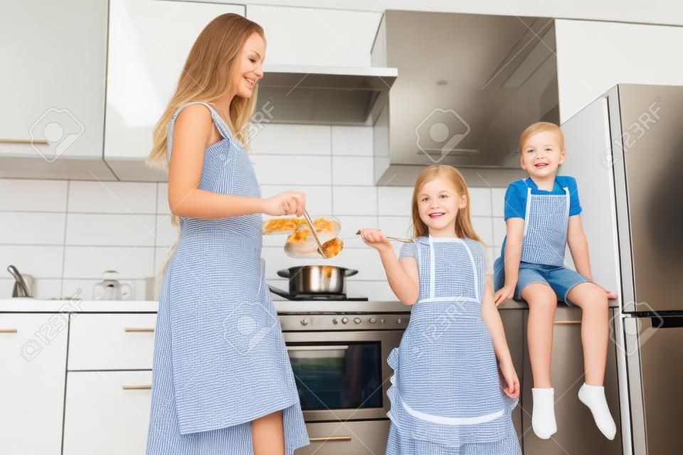 Young woman with her children are cooking meal in the kitchen. Family home shoot.