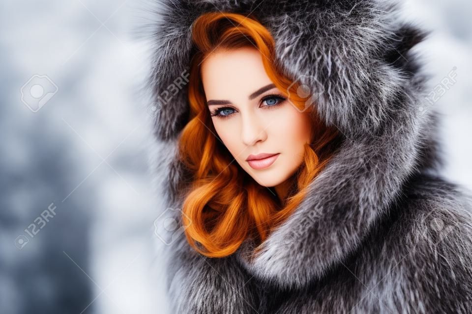 A close up portrait of a beautiful woman wearing a fur coat with hood. Beauty, winter fashion, style.