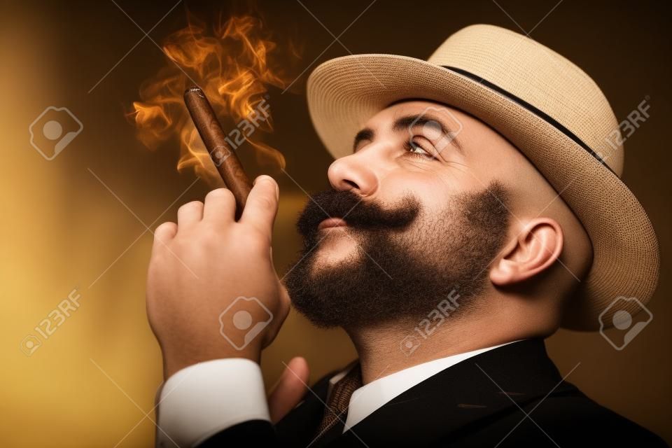 A close up portrait of a thoughtful man with a cigar posing in the vintage interior. Men's beauty, fashion, style.
