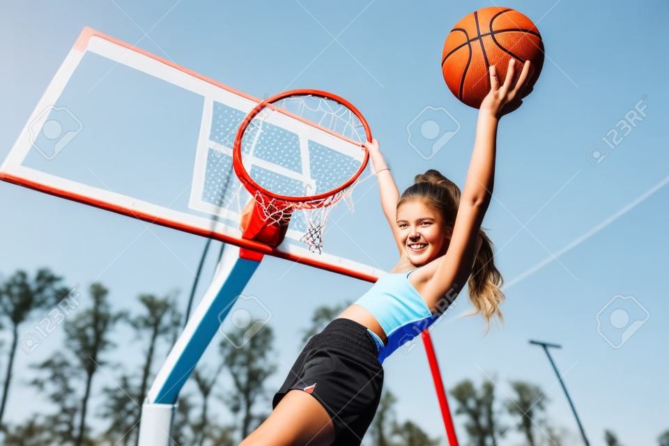 Um retrato de uma adolescente esportiva posando na pitada de basquete. Moda esportiva, estilo de vida ativo, basquete.