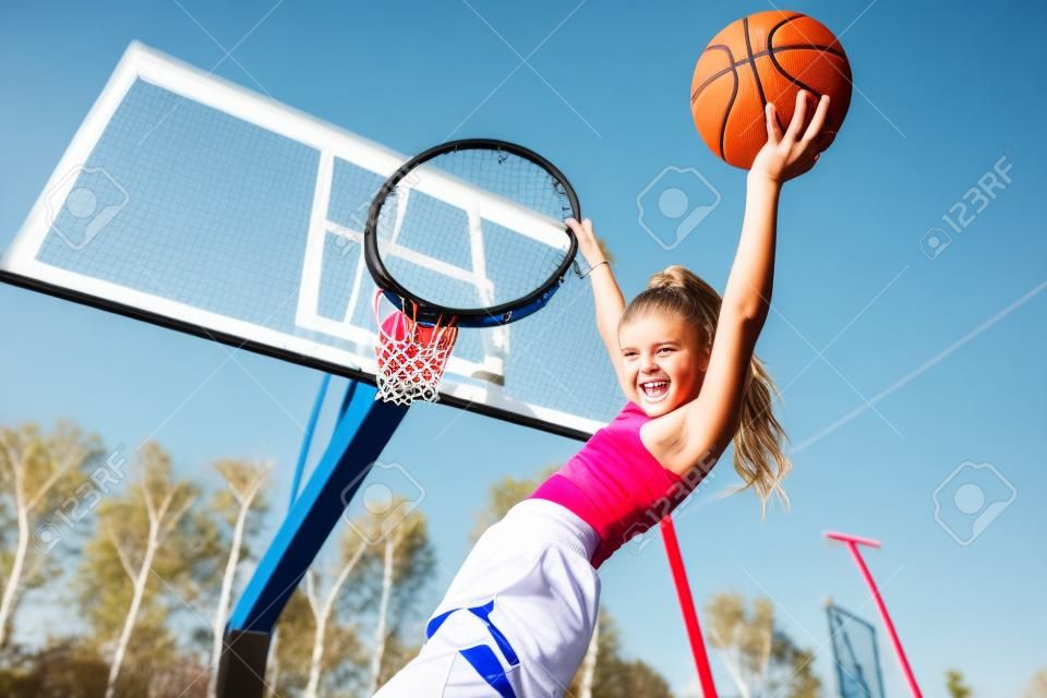 Ein Porträt eines sportlichen Jugendlichmädchens, das auf der Basketballprise aufwirft. Sportmode, aktiver Lebensstil, Basketball.