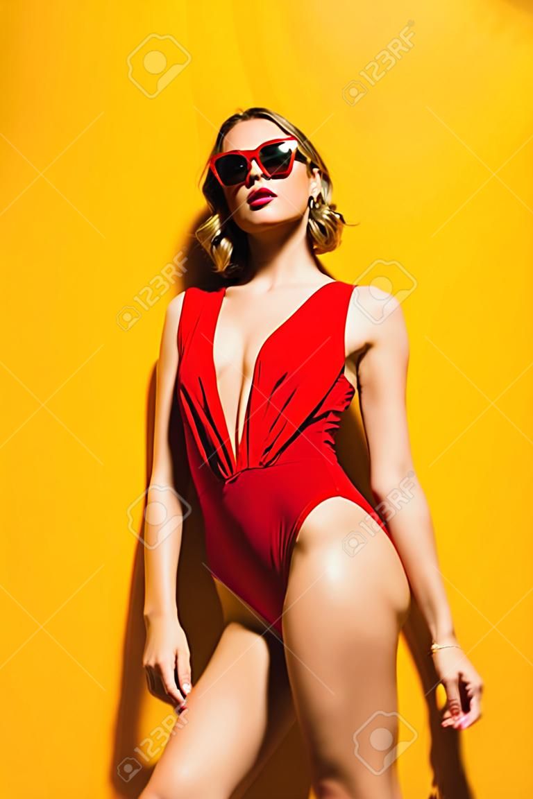 수영복을 입고 노란색 배경 위에 포즈를 취하는 밝은 소녀의 초상화. 여름 패션, 뷰티.