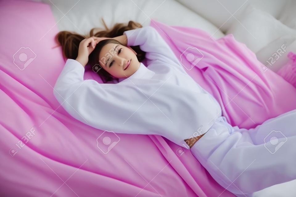 Retrato de una linda adolescente acostada en la cama en el dormitorio. Belleza, moda.
