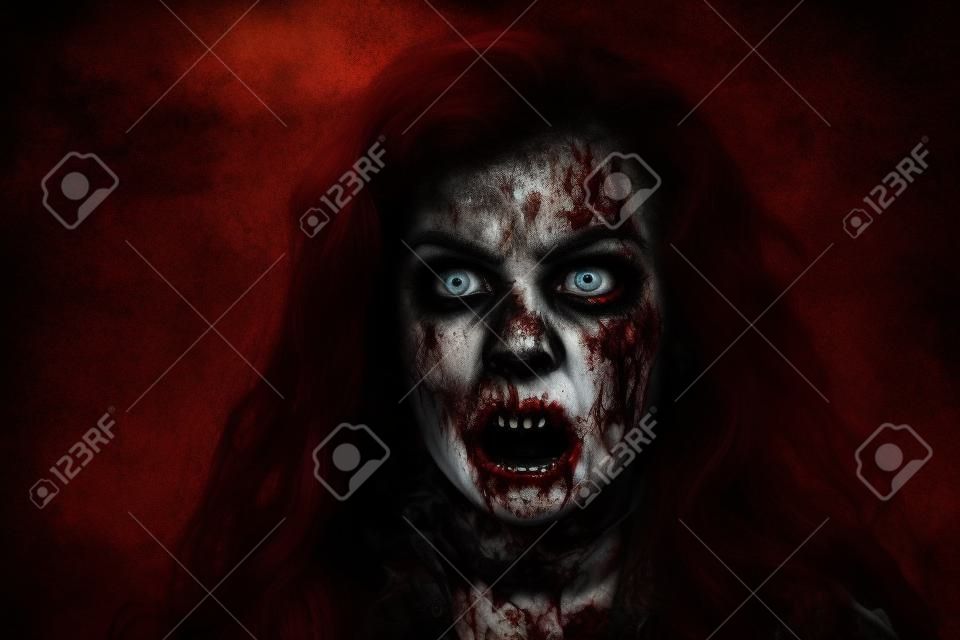 Portrait of a bloodthirsty zombie woman with faded eyes looking up and opening her bloody mouth. Devil possessed woman. Horror, thriller. Halloween.