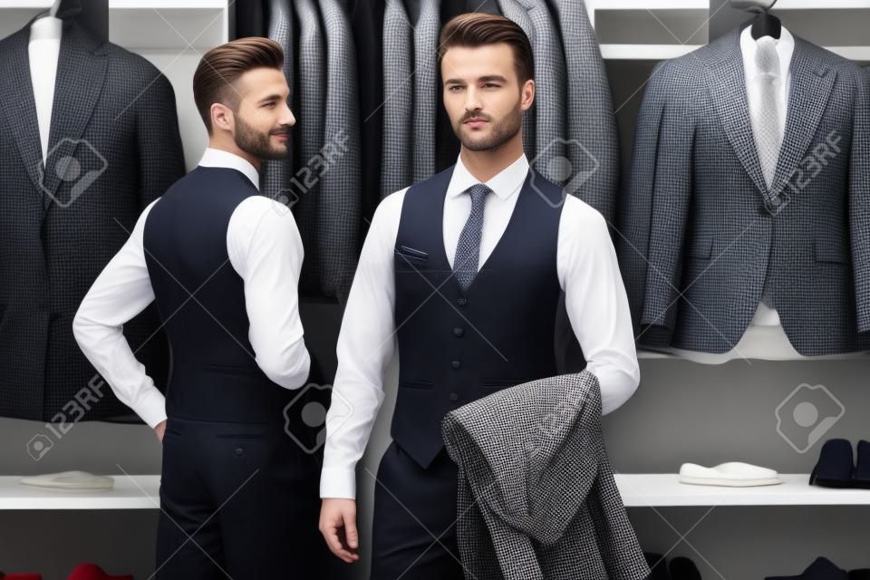 고급 남성 의류 매장에서 우아한 클래식 정장을 입은 잘생긴 두 남자의 초상화. 비즈니스 스타일. 남자 패션.