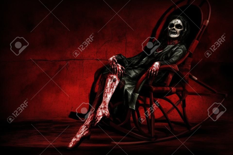 Uma mulher terrível, possuída pelo diabo, senta-se em uma cadeira de balanço contra uma parede de concreto pingando com sangue. Mulher zumbi assustador. Horror, thriller. Halloween.