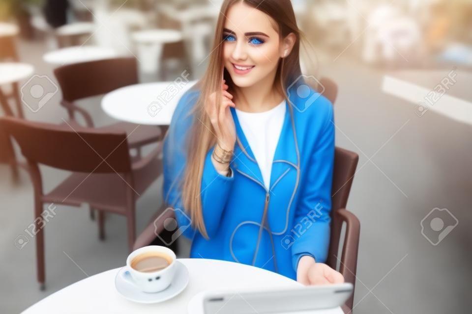 美麗的藍眼睛的女孩與平板電腦的咖啡館