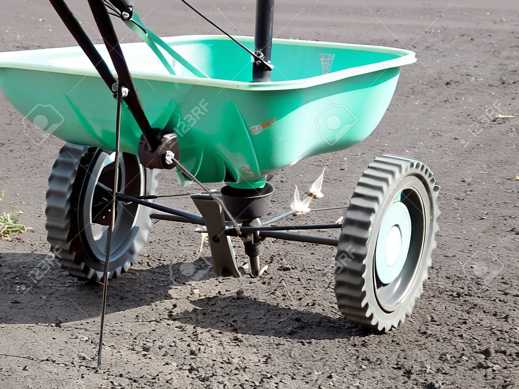 Manually operated seeder filled with grass seeds shot on soil