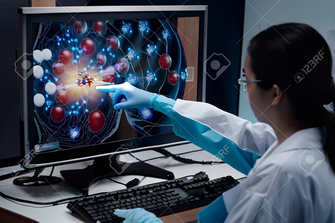 Une chercheuse indique la position de l'échantillon de médicament dans la simulation de modélisation du développement de médicaments, comme indiqué sur un écran d'ordinateur. L'ordinateur analytique est un superordinateur pour la simulation de médicaments.