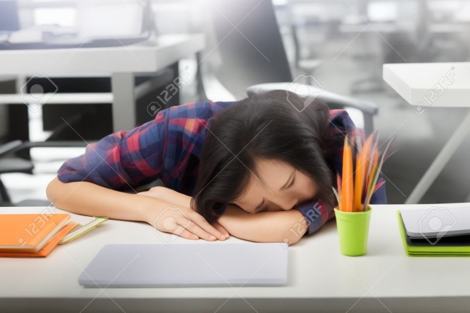 Frau, die am Arbeitsplatz schläft. Mädchen müde erschöpft von harter Arbeit