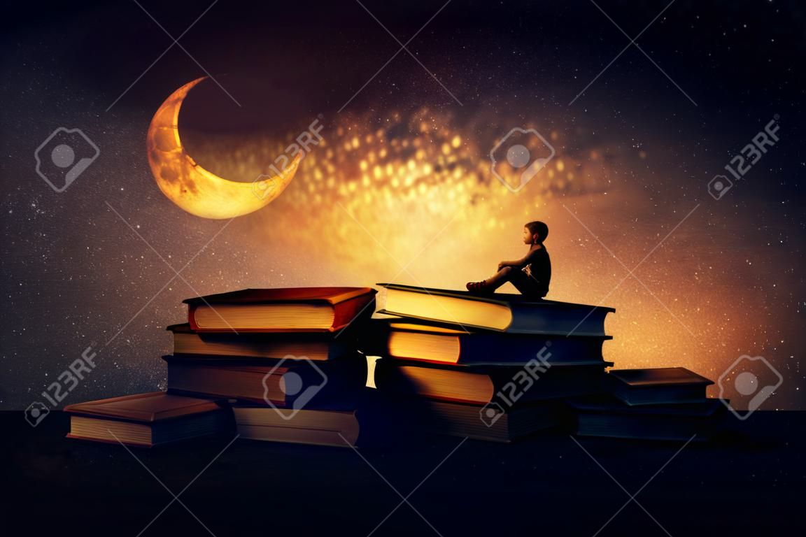 Chłopiec siedział sam na stos książek, patrząc nowiu. Magiczna noc sceny. W poszukiwaniu wiedzy, pojmowania koncepcji.