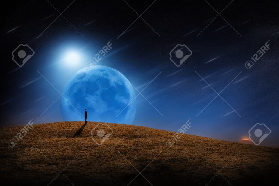 Scène du monde surréaliste avec une silhouette de personne, seule sur une terre vide et sèche, regardant le ciel nocturne étoilé avec des comètes tombant, sur un fond de pleine lune. Phénomène spatial, paysage conceptuel.