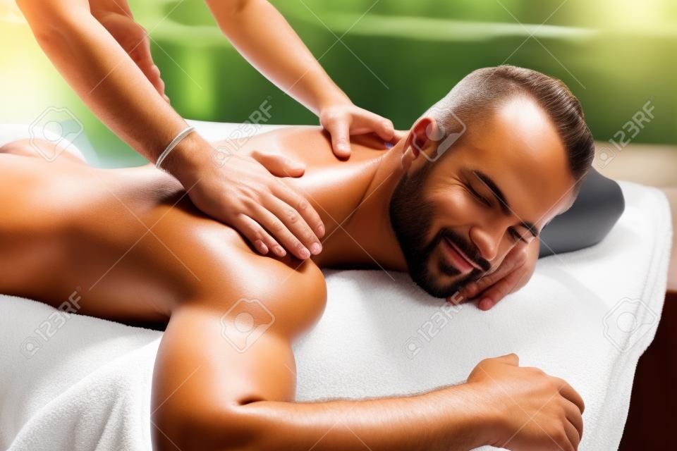Spa Massage pour l'homme. Close Up Of Handsome sain Sourire homme appréciant Massage relaxant du dos à l'extérieur Salon de beauté. Masseuse Masser Body Homme Avec Oil Aromathérapie. Soins de la peau Traitement Concept