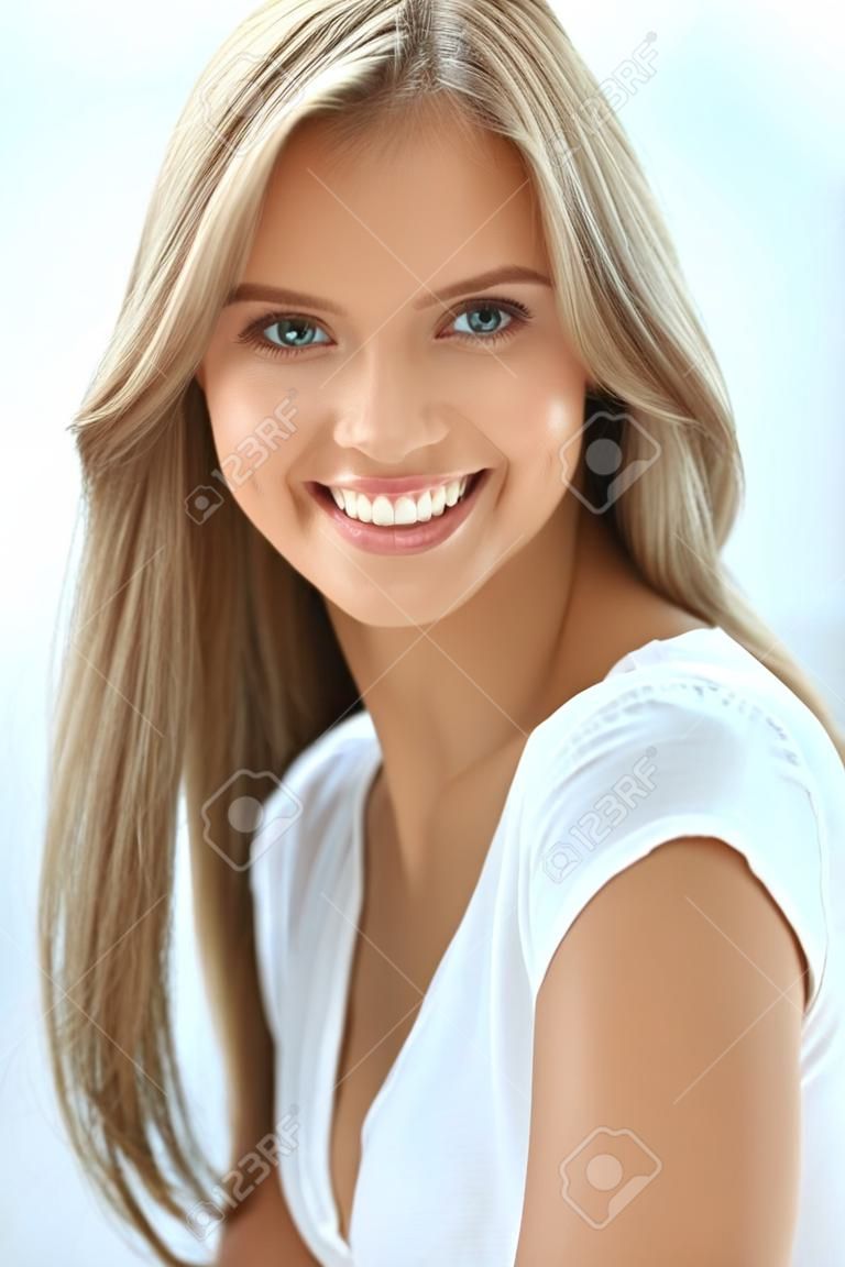 Retrato da mulher da beleza. Closeup da menina feliz bonita com sorriso perfeito, dentes brancos que sorriem na câmera. Mulher jovem saudável atrativa com dentro de casa da composição natural fresca da cara. Imagem de alta resolução