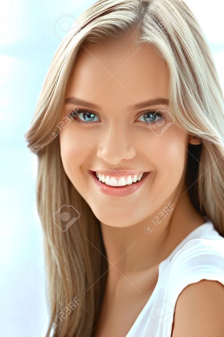 Schoonheid vrouw portret. Close-up van mooi gelukkig meisje met perfecte glimlach, witte tanden glimlachen op camera. Aantrekkelijke gezonde jonge vrouw met fris natuurlijk gezicht make-up binnen. Hoge resolutie Afbeelding