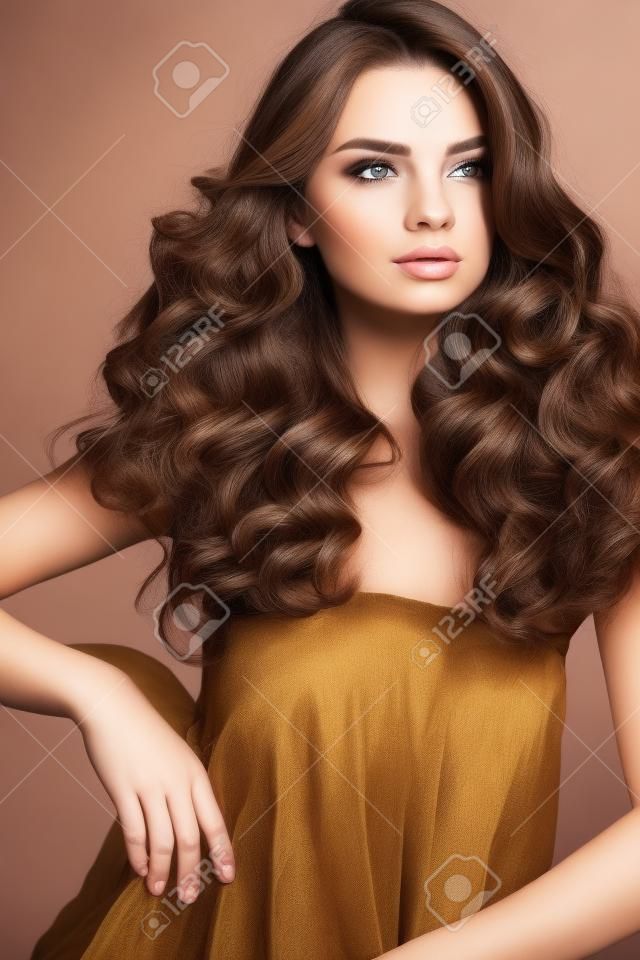 Hair Style. Belle femme avec la santé à long Wavy cheveux bouclés et le maquillage du visage magnifique. Portrait de Brunette fille modèle avec Coiffure Mode, Marron Couleur des cheveux et parfait Curls. Beauté. Haute qualité