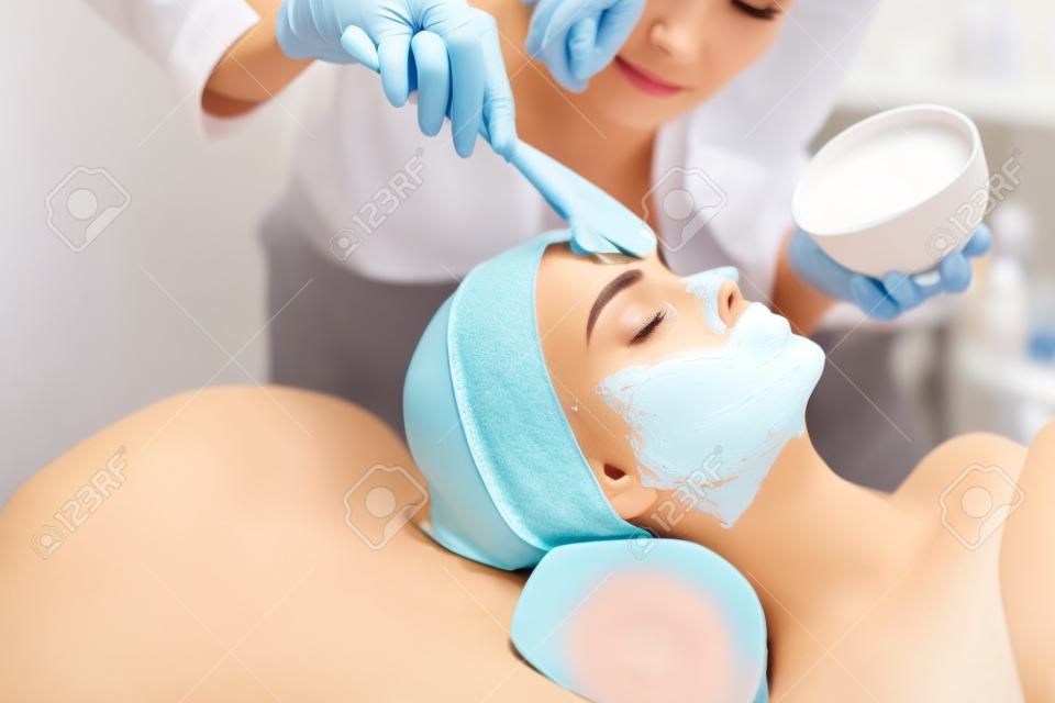 Facial Skin Treatment. ?loseup Of Beautiful Young Woman Receiving Cosmetic Mask In Beauty Salon. Beautician Applying Alginate Mask On Female Face With Smooth Soft Skin. Cosmetology. High Resolution