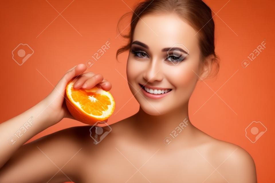 Beauty. Woman with radiant face skin squeezing orange portrait