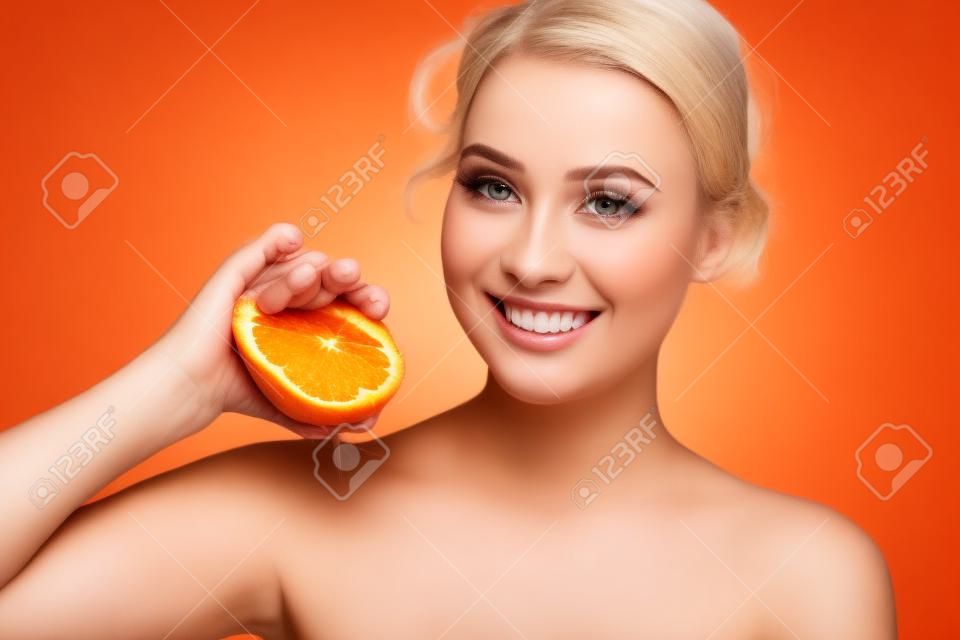 Beauty. Woman with radiant face skin squeezing orange portrait