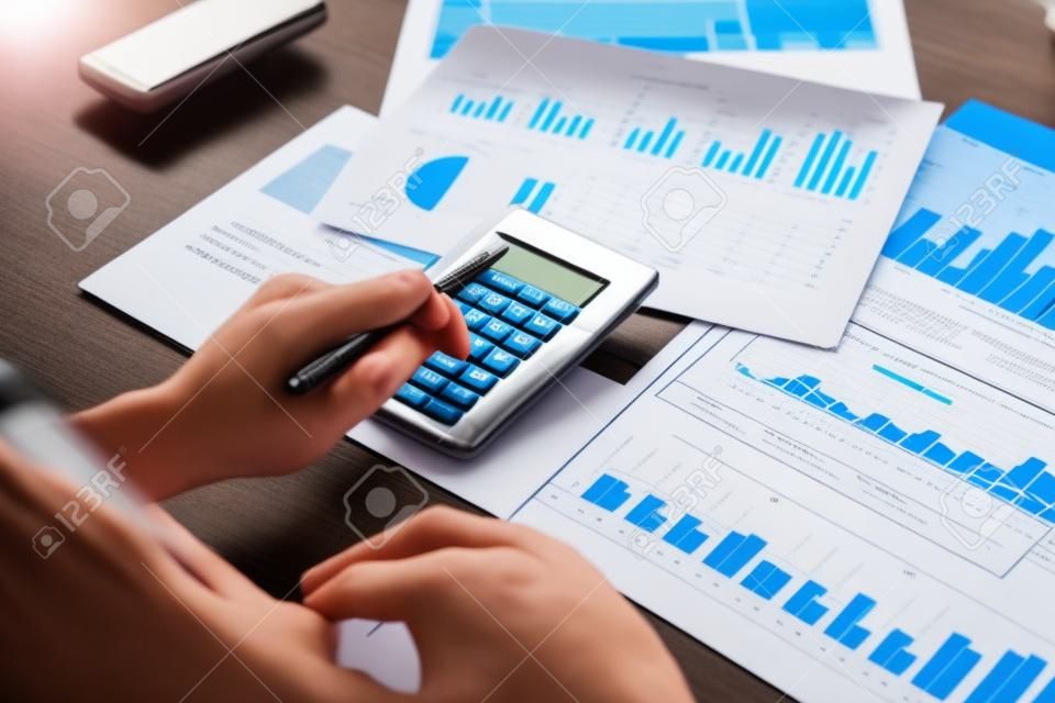 Accounting zakenlieden berekenen vennootschapsbelasting met rekenmachines en grafieken op de bureaus, Financiële en bancaire winst analyse concept.