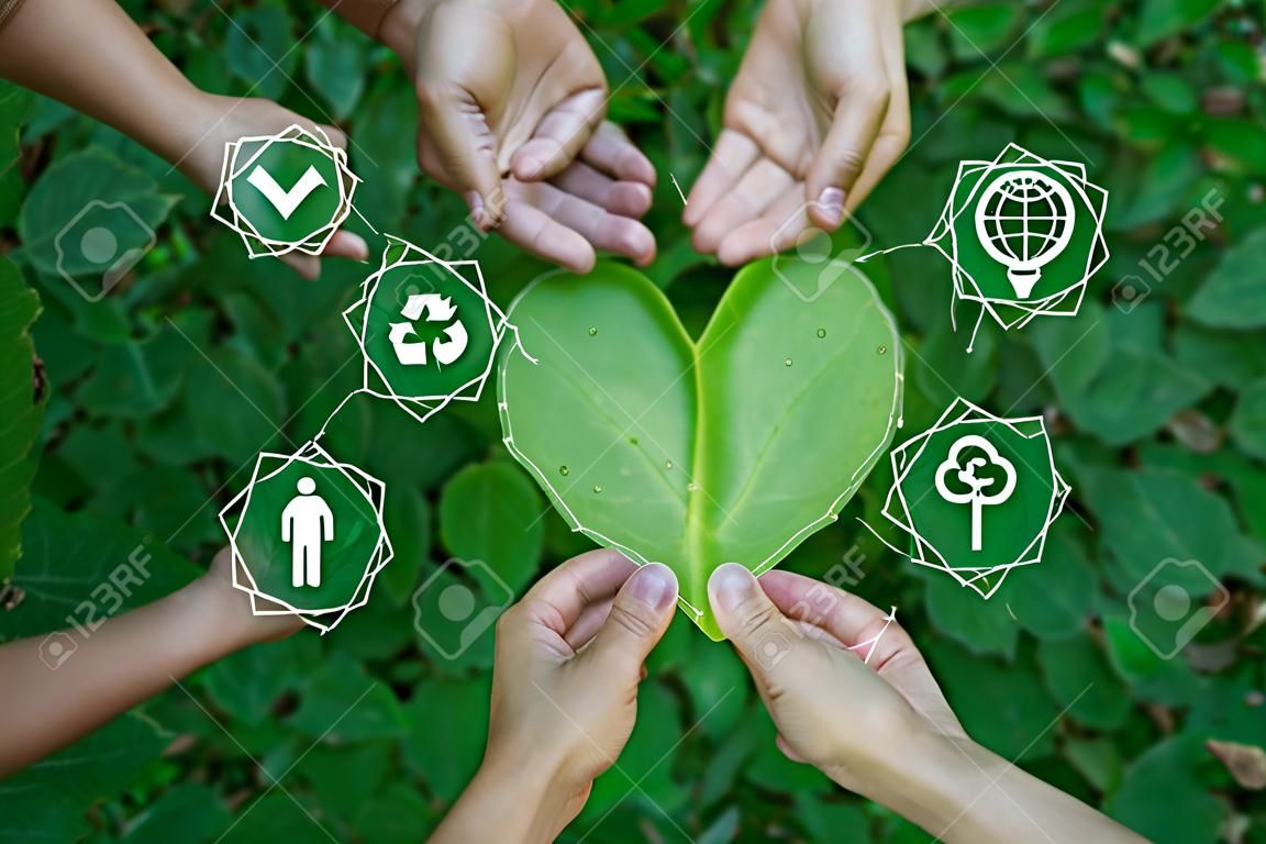 ESG concept of environmental, social and governance.Group of people holding heart shaped leaves with ESG icon.