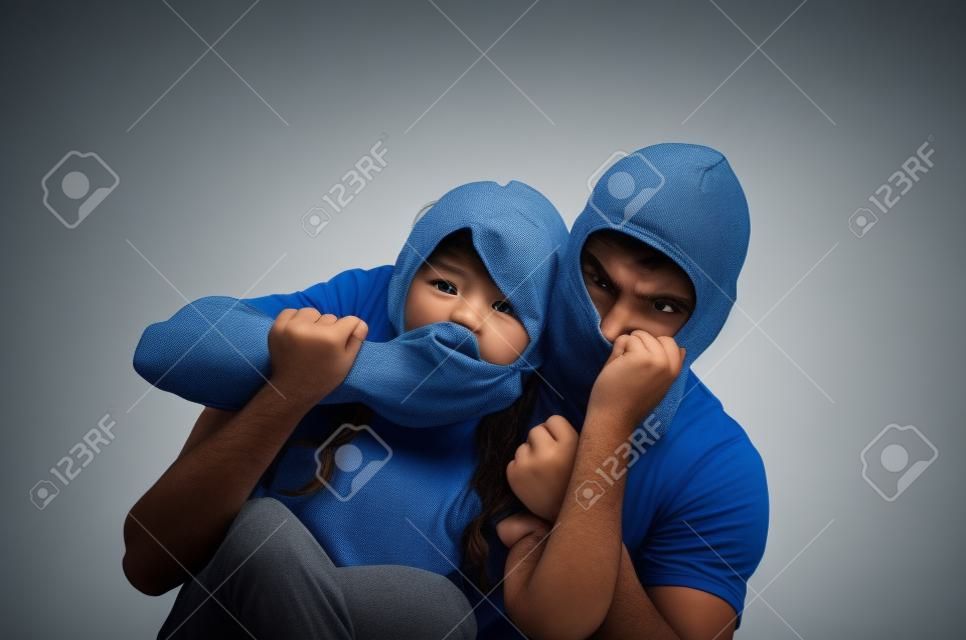 male angry masked thief holding silencing kidnapping young scared girl isolated on white