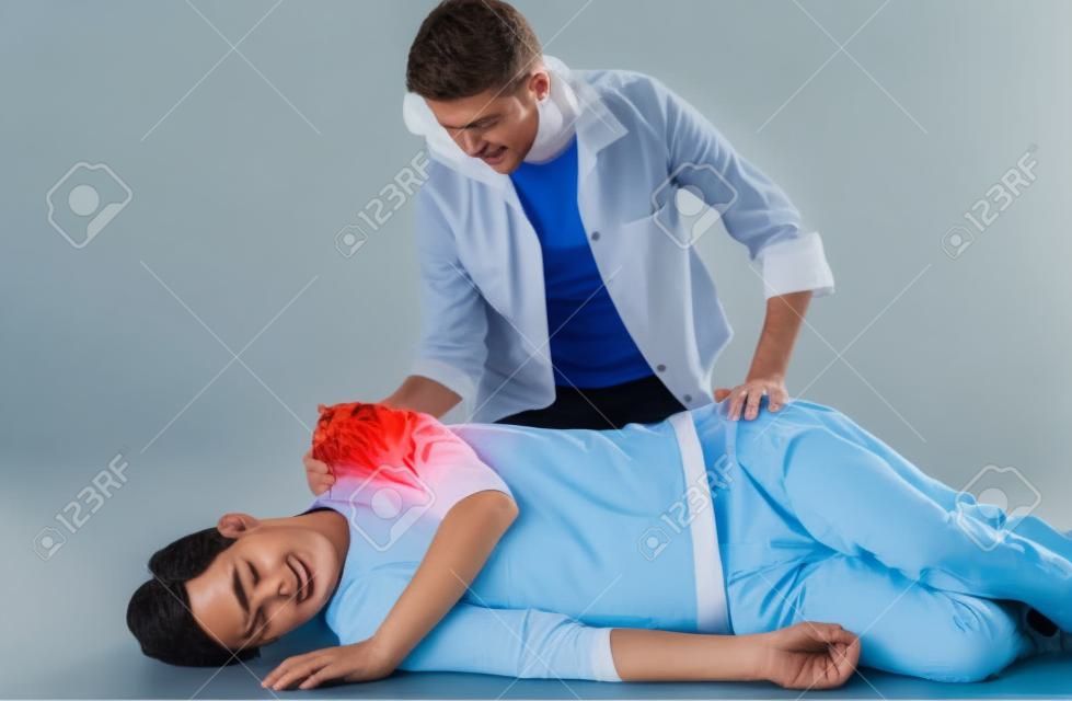 Çift erkek hasta kurtarma pozisyonunda yatarken ve dişi onunla üstünde oturan ilk yardım tekniklerini gösteren.