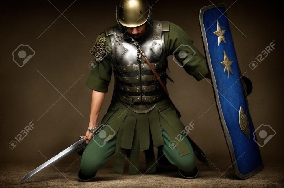 müde Soldat kniend mit einem Schild und ein Schwert in der Hand