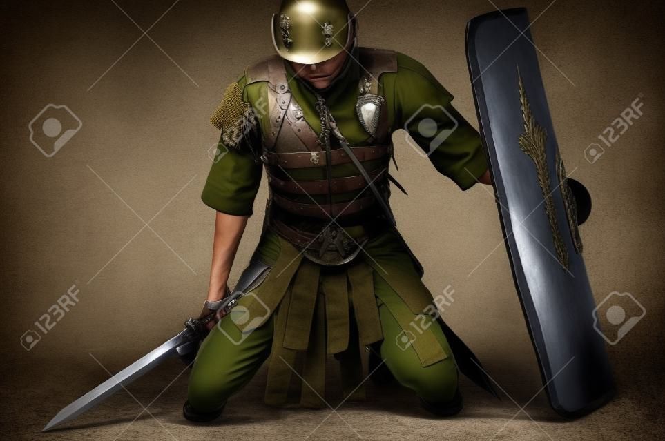 soldado cansado de rodillas con un escudo y una espada en las manos