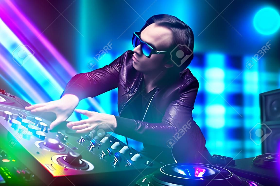 Mezclar música dj joven en un club con luces de color azul y morado