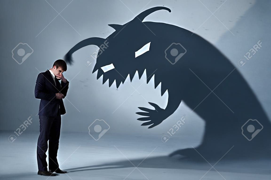Hombre de negocios temeroso de su propio concepto de monstruo de sombra sobre fondo sucio