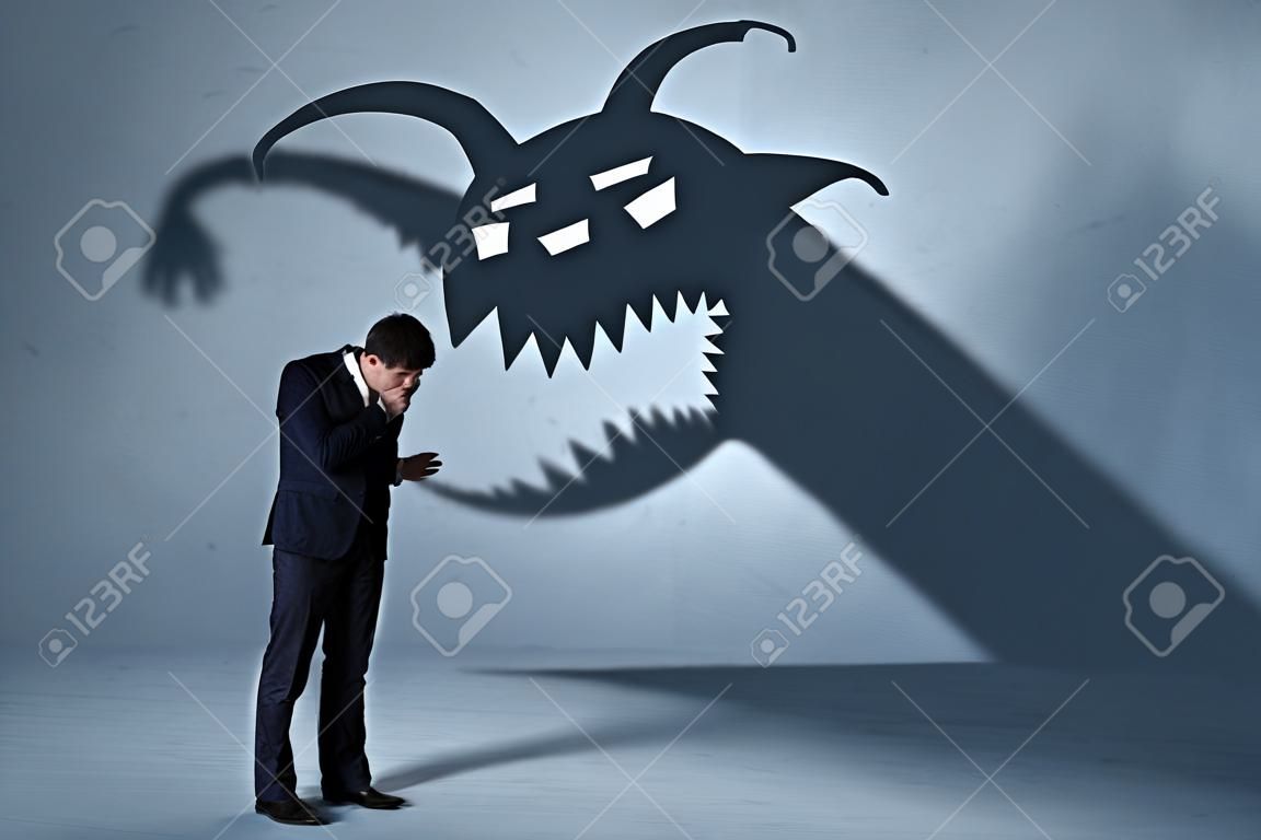 Business man afraid of his own shadow monster concept on grungy background