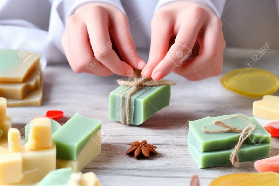 Woman is packing handmade natural soap as a gift for New Year and Christmas. Concept of preparing for holidays, hobbies, a cozy festive atmosphere.