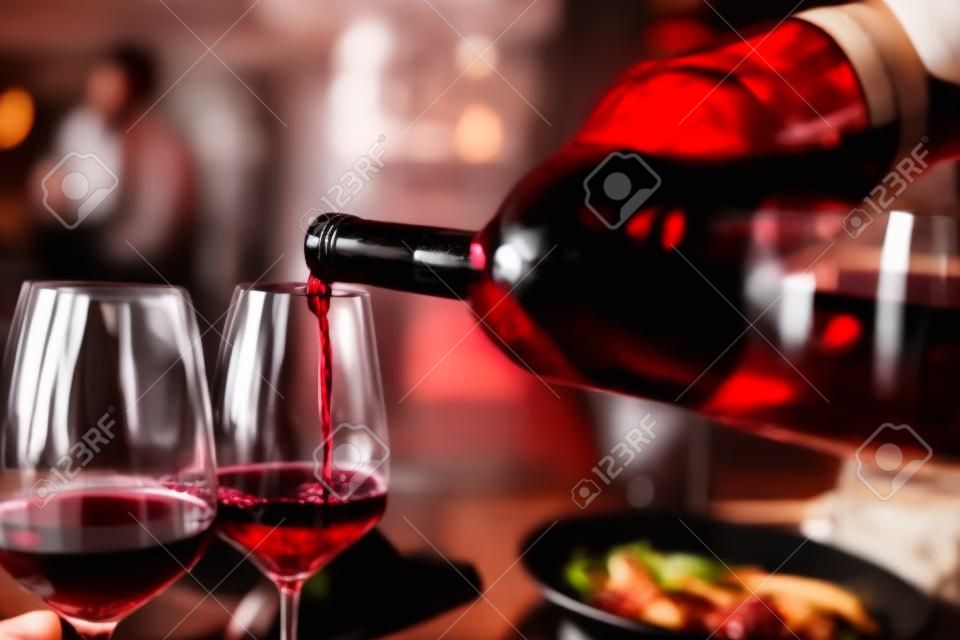 Persoon die rode wijn in een restaurant giet