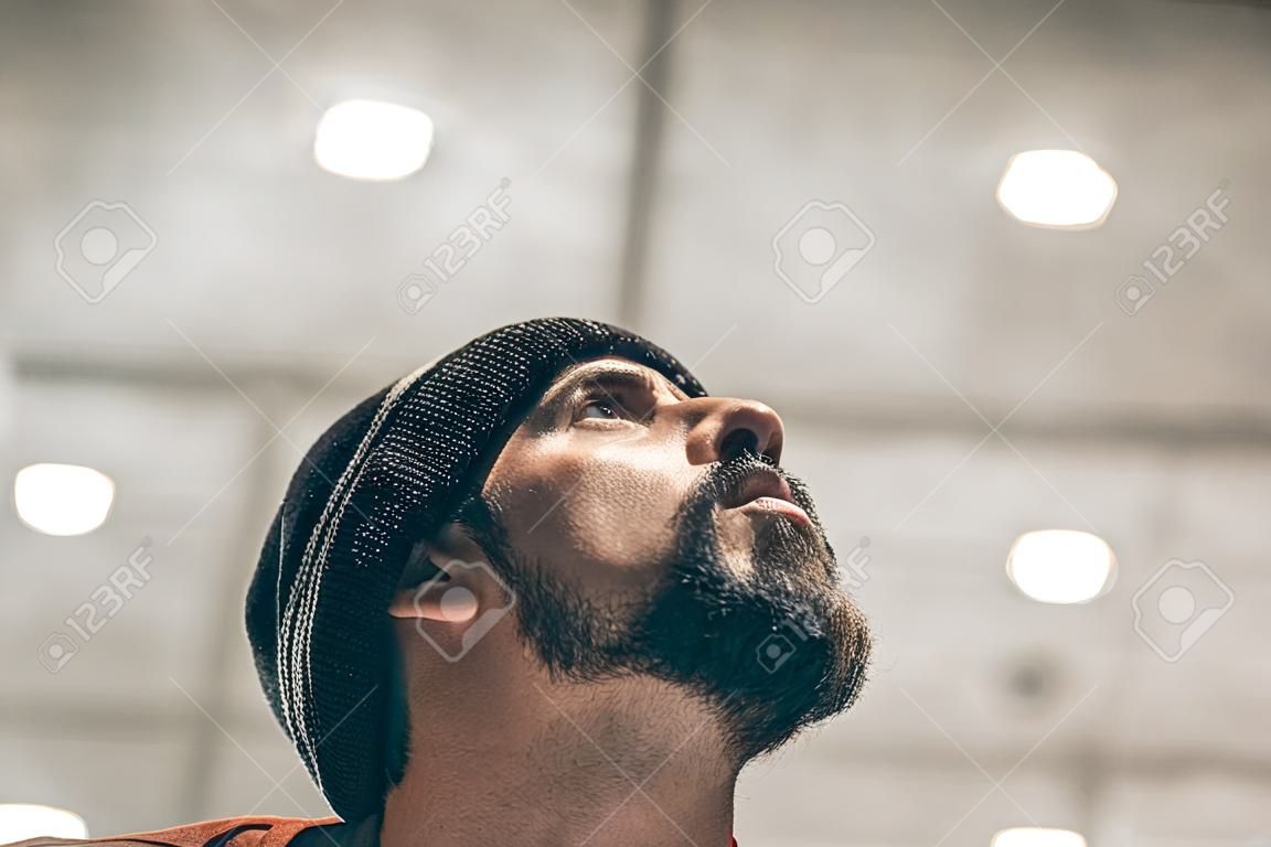 Portrait of a handsome man with a beard and hat. Looking at the sky