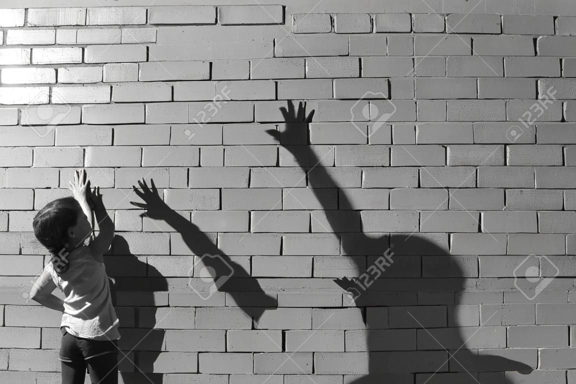 Mała dziewczynka grać z jej cień na ścianę. (BW)