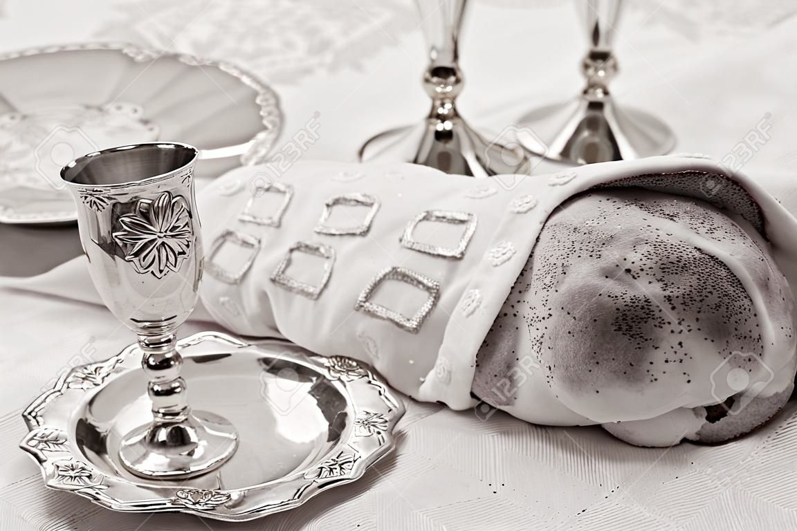 Mesa de víspera de Shabat con pan jalá cubierto, velas sabáticas y Kidush taza de vino. (BW)